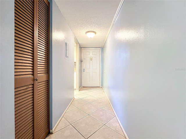 corridor featuring light tile patterned flooring and a textured ceiling