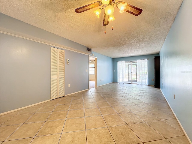 tiled empty room featuring ceiling fan and a textured ceiling