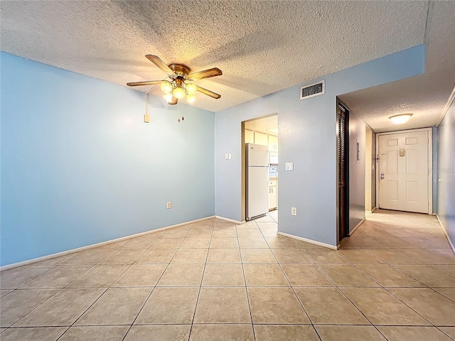 tiled empty room featuring ceiling fan and a textured ceiling