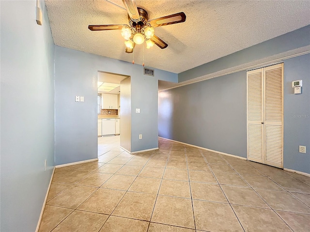 spare room with ceiling fan, a textured ceiling, and light tile patterned floors