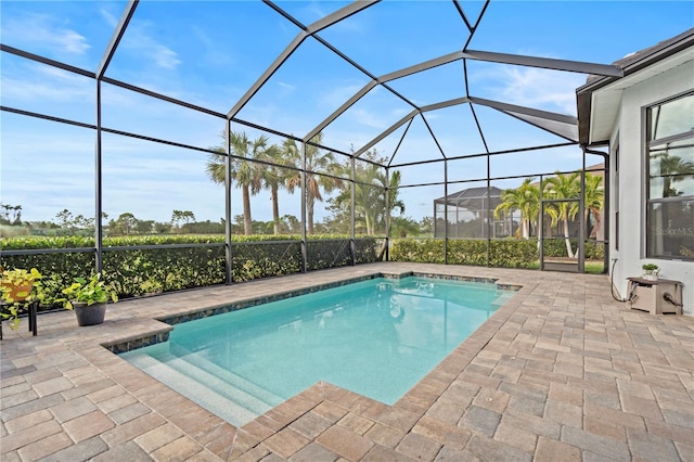 view of pool featuring glass enclosure and a patio area