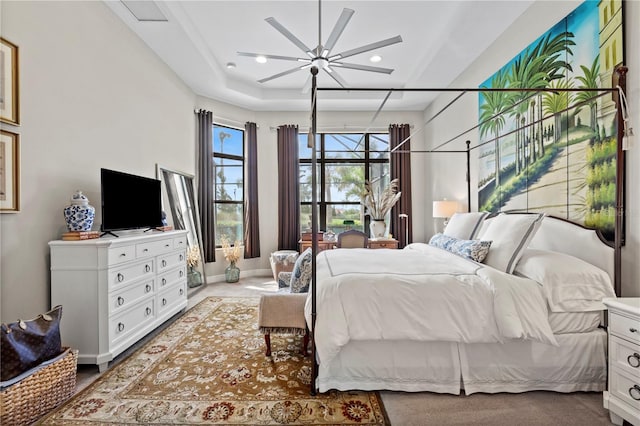 bedroom featuring a raised ceiling and ceiling fan with notable chandelier