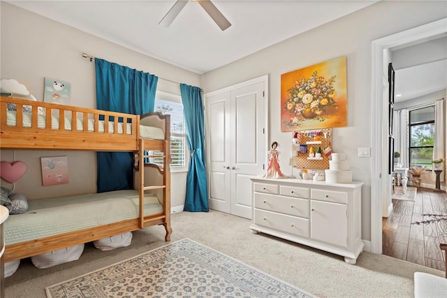 bedroom with ceiling fan, light carpet, and a closet