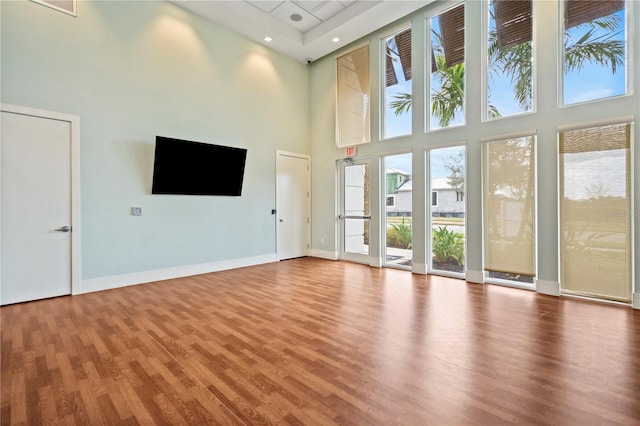 unfurnished living room featuring hardwood / wood-style floors and a towering ceiling