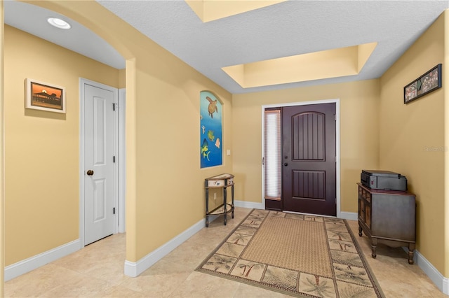 tiled foyer featuring a tray ceiling