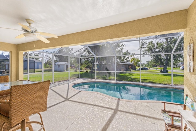 view of pool with a lawn, ceiling fan, a patio area, and a lanai