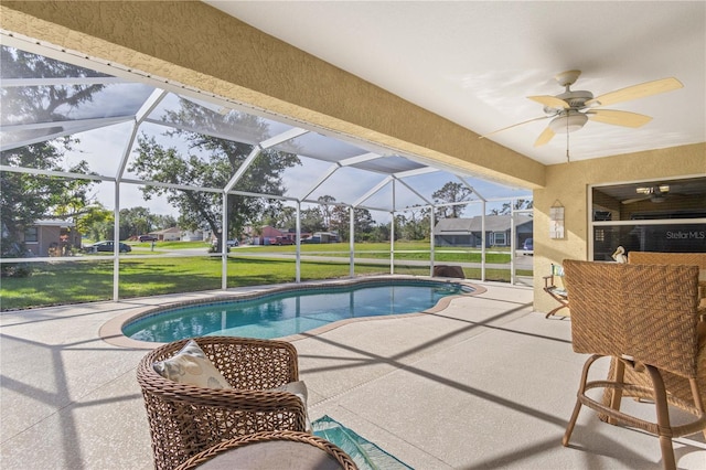 view of pool with a lanai, a patio area, ceiling fan, and a yard