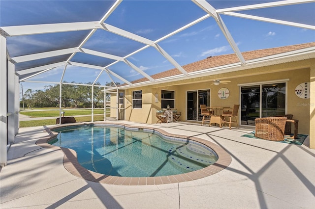 view of swimming pool with glass enclosure, ceiling fan, and a patio