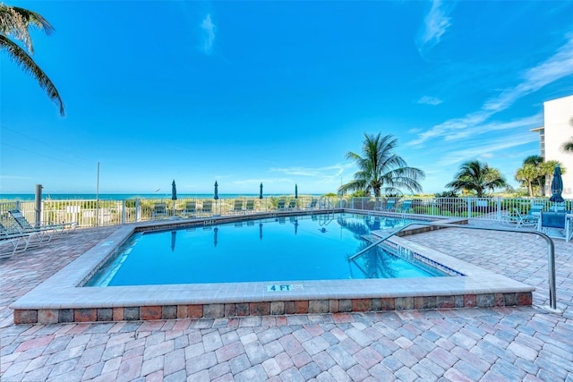 view of swimming pool with a patio area and a water view