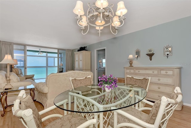 dining area with ceiling fan with notable chandelier, floor to ceiling windows, a water view, and light hardwood / wood-style flooring