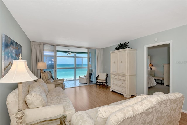 living room with a water view, light hardwood / wood-style flooring, expansive windows, and ceiling fan