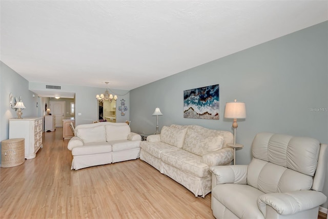 living room with light hardwood / wood-style flooring and a notable chandelier