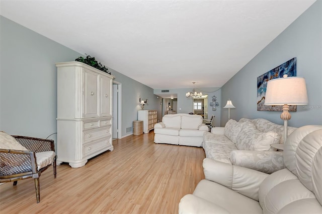 living room with light hardwood / wood-style floors and a notable chandelier