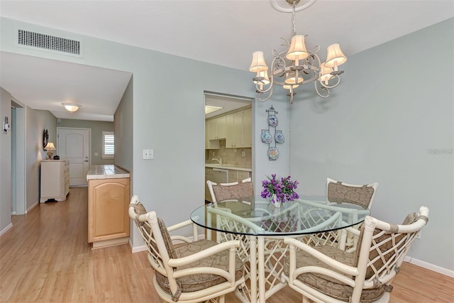 dining space with an inviting chandelier and light hardwood / wood-style flooring