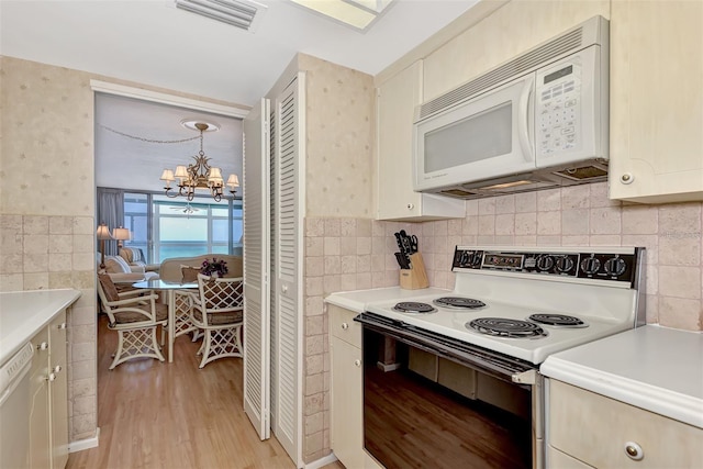 kitchen with decorative light fixtures, white appliances, light hardwood / wood-style flooring, and an inviting chandelier