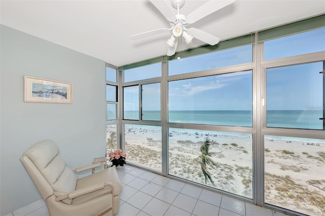 sunroom featuring a beach view, a water view, and ceiling fan