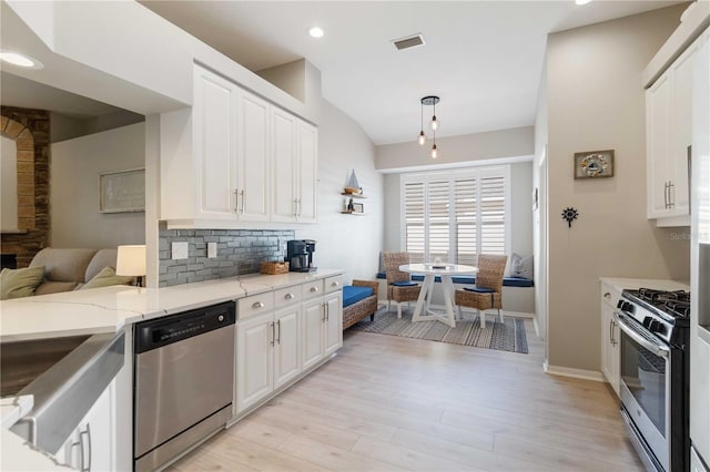 kitchen featuring backsplash, light stone countertops, light hardwood / wood-style floors, white cabinetry, and stainless steel appliances