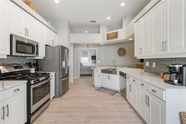 kitchen featuring kitchen peninsula, white cabinetry, sink, and stainless steel appliances