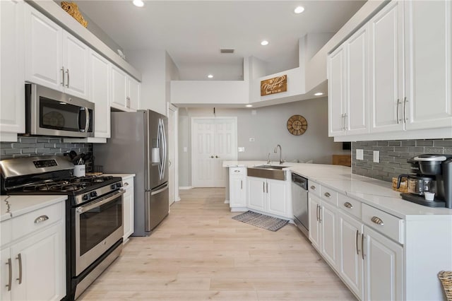 kitchen featuring white cabinets, appliances with stainless steel finishes, kitchen peninsula, and light hardwood / wood-style floors