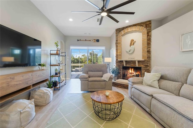 living room with a fireplace, wood-type flooring, and ceiling fan