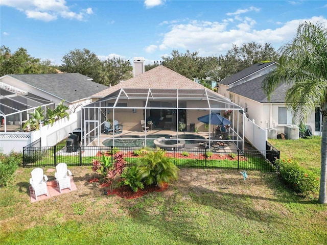 back of property with a lanai, a pool with hot tub, central AC, a patio area, and a lawn