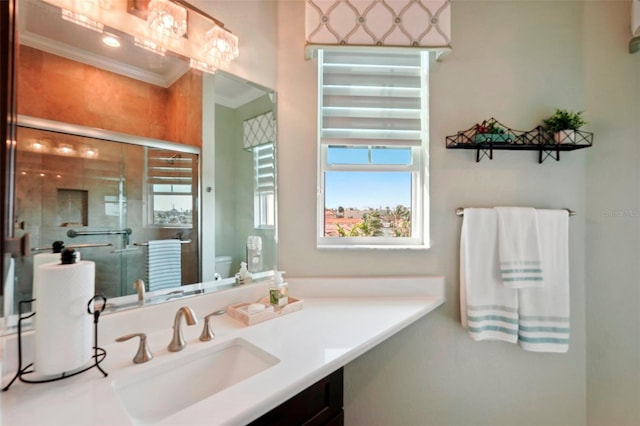 bathroom featuring a shower with shower door, vanity, toilet, and crown molding