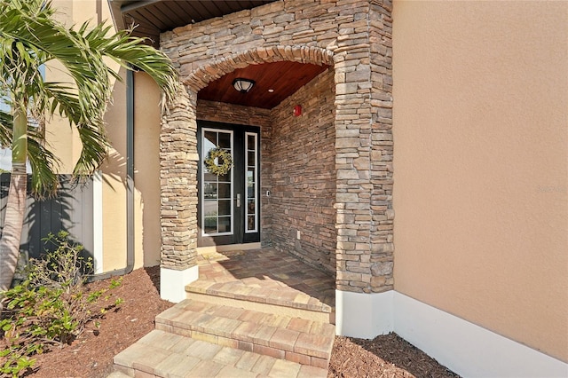 entrance to property featuring stone siding and stucco siding