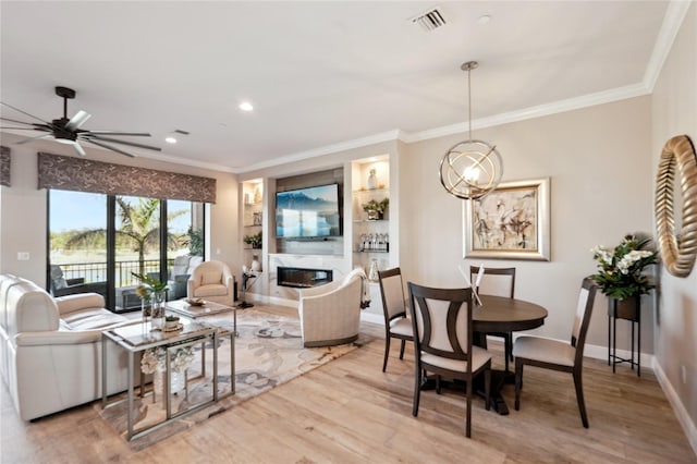 living area with light wood finished floors, a high end fireplace, visible vents, and crown molding