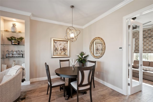 dining space featuring built in features, hardwood / wood-style flooring, a chandelier, and ornamental molding