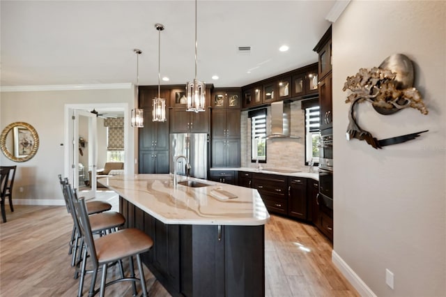 kitchen with ceiling fan, backsplash, pendant lighting, a kitchen island with sink, and stainless steel fridge