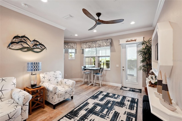 living area with ceiling fan, a healthy amount of sunlight, light hardwood / wood-style flooring, and crown molding