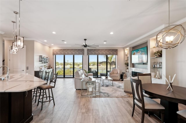 dining space with ceiling fan, sink, crown molding, and hardwood / wood-style floors