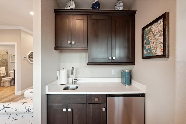 bar with stainless steel dishwasher, sink, dark brown cabinetry, and crown molding