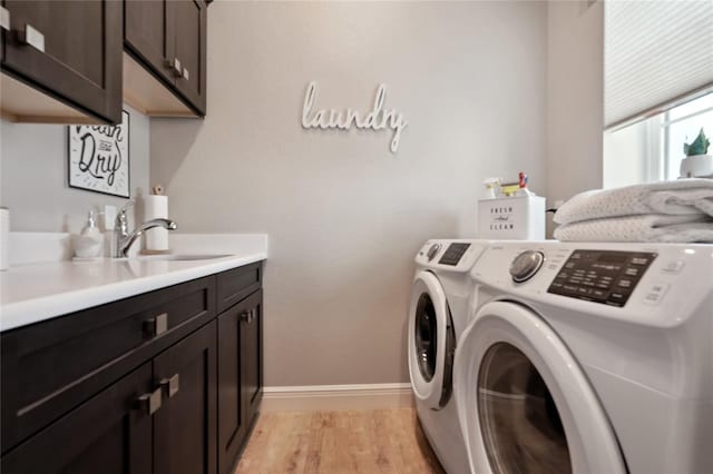 laundry area with cabinets, light hardwood / wood-style flooring, separate washer and dryer, and sink