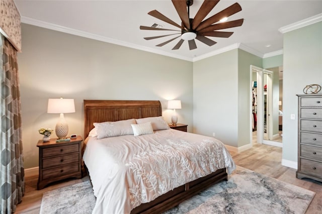 bedroom with baseboards, a spacious closet, light wood-style flooring, and crown molding