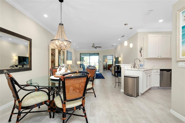 dining space with ceiling fan with notable chandelier, ornamental molding, and sink