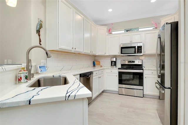 kitchen featuring backsplash, white cabinets, sink, appliances with stainless steel finishes, and kitchen peninsula