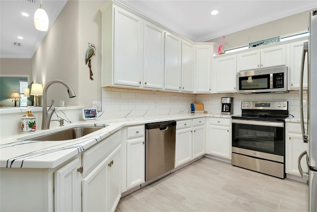 kitchen featuring appliances with stainless steel finishes, backsplash, sink, white cabinetry, and hanging light fixtures