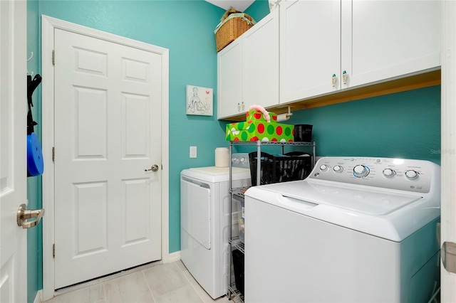 clothes washing area featuring cabinets and washer and dryer