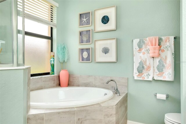 bathroom with toilet and tiled tub