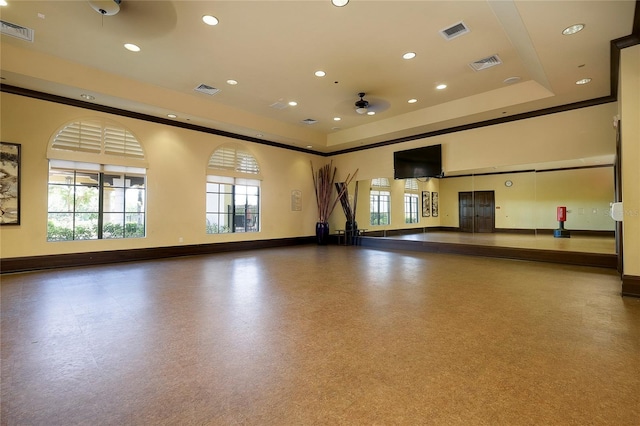 exercise room featuring a tray ceiling and ceiling fan