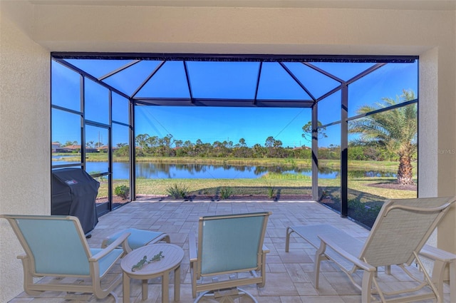 view of patio featuring grilling area, a water view, and glass enclosure