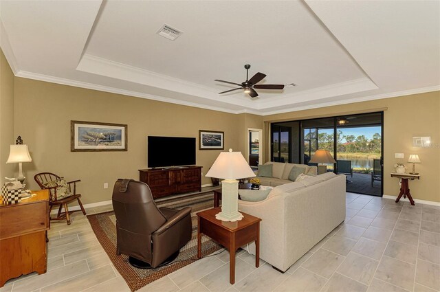 living room featuring a raised ceiling, ceiling fan, and ornamental molding