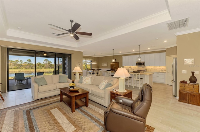 living room with a tray ceiling, ceiling fan, and ornamental molding