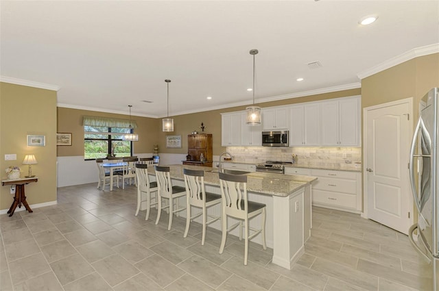 kitchen with pendant lighting, a center island with sink, white cabinets, light stone countertops, and stainless steel appliances