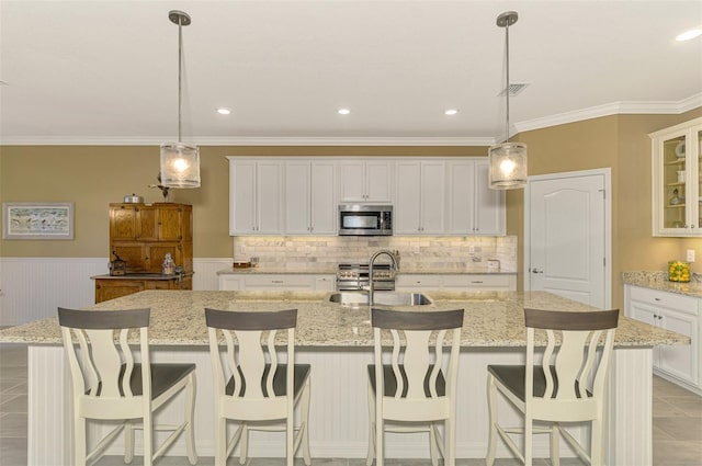 kitchen with white cabinetry, sink, stainless steel appliances, and a center island with sink