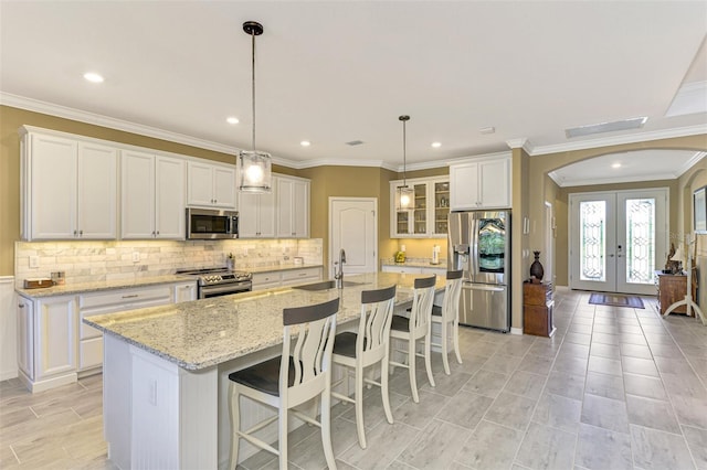 kitchen with stainless steel appliances, white cabinetry, and a kitchen island with sink