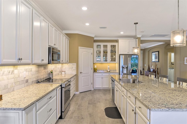 kitchen featuring pendant lighting, white cabinets, sink, an island with sink, and appliances with stainless steel finishes