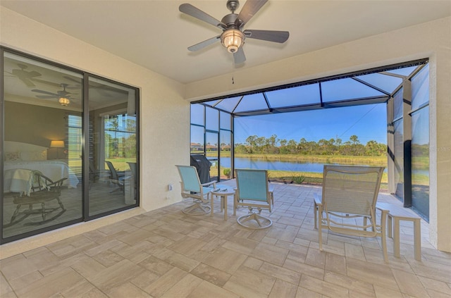 view of patio / terrace with a water view, ceiling fan, and a lanai