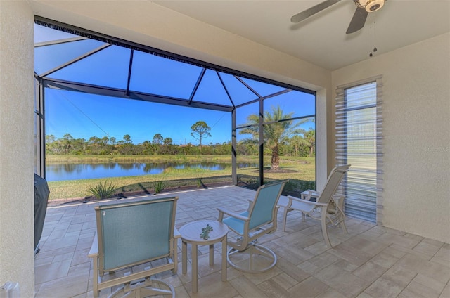 view of patio with a lanai, ceiling fan, and a water view